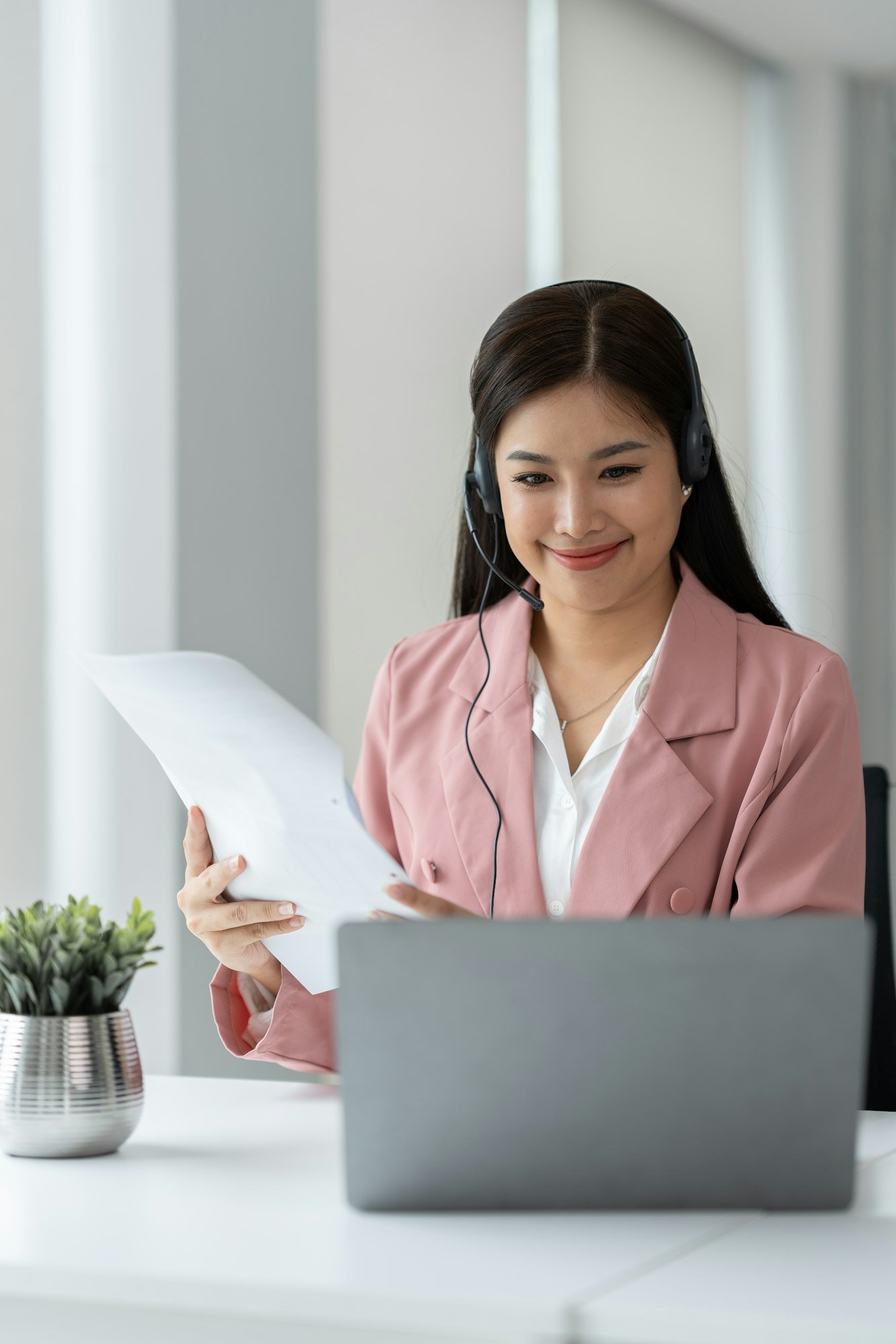 Asian businesswoman employee or executive using laptop computer and wearing headset video call expla